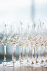 Several rows clear, clean glasses for wine and champagne on counter prepared for drinks.