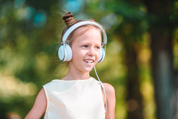 Little adorable girl listening music in the park
