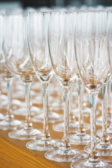 Several rows clear, clean glasses for wine and champagne on counter prepared for drinks.