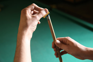 Young woman with cue and chalk before playing billiard