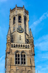 Fototapeta na wymiar Belfry of Bruges, the medieval bell tower against blue sky. The 83 meter high belfry or hallstower (halletoren) is Bruges' most well-known landmark and its most symbolic civil monument.