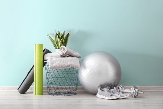 Set of sports equipment with fitness ball, towels and shoes near wall