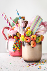 Different delicious freak shakes on light background