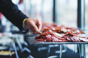 Thinly sliced sausage slices on a black stone board. 