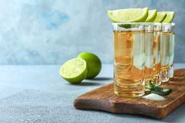 Glasses of tasty tequila on color background