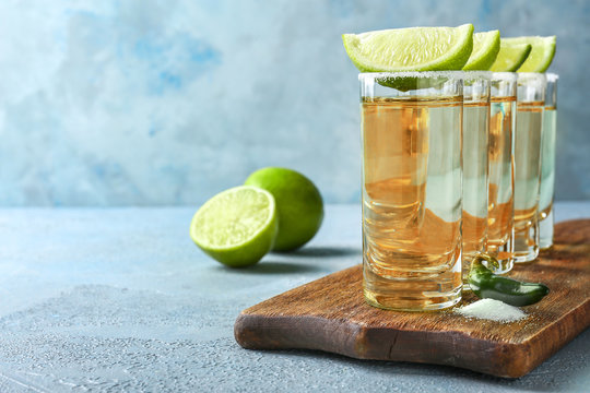 Glasses of tasty tequila on color background