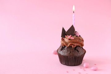 Tasty chocolate cupcake with candle on color background