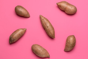 Fresh sweet potatoes on color background