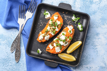 Baked sweet potato with cheese and arugula on color background