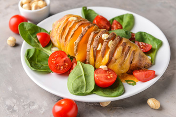 Baked sweet potato with cheese, tomato and nuts on plate