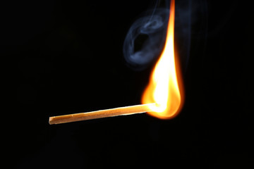 Burning match on dark background
