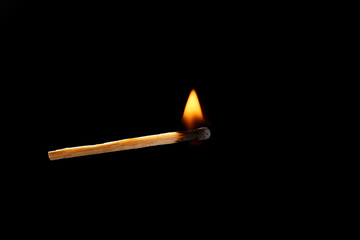 Burning match on dark background