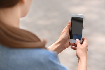 Young woman with mobile phone outdoors, closeup