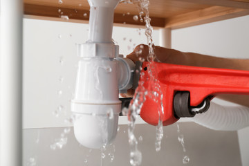 Plumber repairing pipes of kitchen sink, closeup