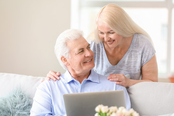 Portrait of happy mature couple with laptop at home