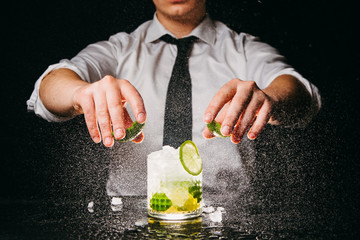 Professional bartender squeezing lime making Caipirinha cocktail
