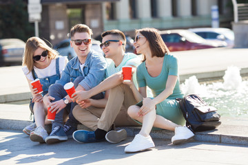 Young attractive people having fun together outdoors. People drinking coffee and smiling. Group of...