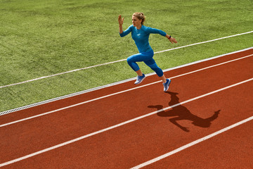 Sportive blonde woman training at open stadium