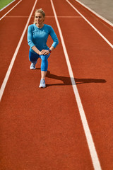 Obraz premium Sportive blonde woman training at open stadium
