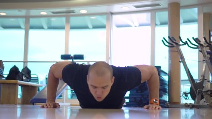 Young sportsman makes pushups exercise with claps in gym