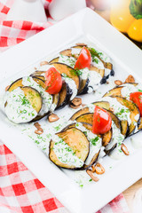 Grilled slices of eggplant and tomatoes in stack with spicy sauce