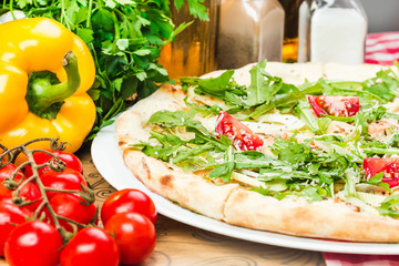 Homemade italian pizza, fresh cherry tomatoes and basil, arugula served on wooden board