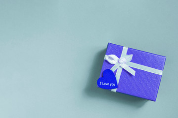 Blue gift box with heart on blue background.