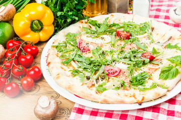 Homemade italian pizza, fresh cherry tomatoes and basil, arugula served on wooden board