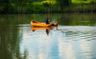 Man in a rubber boat fishing in a river