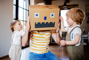 Two toddler children with father playing indoors at home.