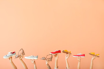 Female hands with different stylish shoes on color background