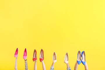 Female hands with different stylish shoes on color background