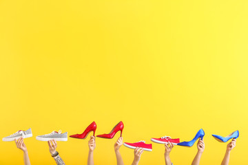 Female hands with different stylish shoes on color background
