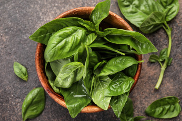 Bowl with fresh basil leaves on table