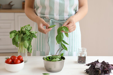 Woman with fresh basil in kitchen