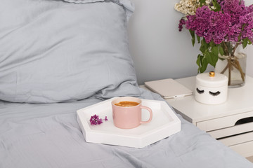 Tray with fresh cup of coffee and macarons dessert standing on the bed