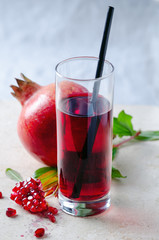 Pomegranate juice  with seeds, fruits and leaves on marble table.