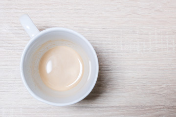 white cup with cappuccino, resting on a table seen from above