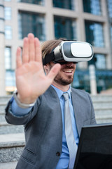 Close up of a young businessman using VR goggles in front of an office building. Selective focus concept, focus on head. Working with modern technologies concept