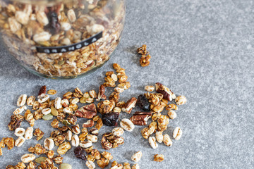 Homemade granola with pecan nuts in glass jar, selective focus, gray background