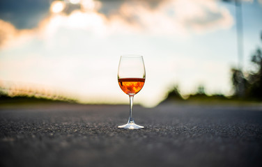 Red rose wine in glass with beautiful sunset reflection and cloudy sky