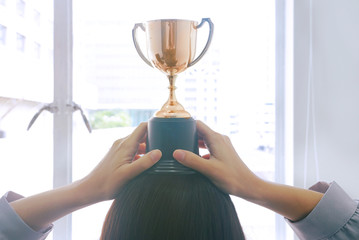 View from back women placed trophies on her heads.