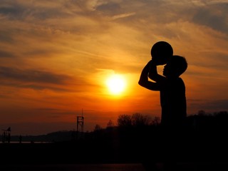 男性がバスケのシュートを決めようとしている場面のシルエット