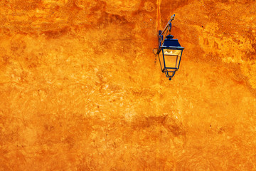 Orange color of the weathered wall with a traditional lantern painted dark green and with its shadow. Rabat, Morocco.