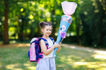 Happy little kid girl with backpack or satchel and big school bag or cone traditional in Germany...