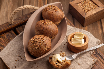 Low-carb gluten-free buns baked with coriander seeds. Served with butter on a wooden tray and a...