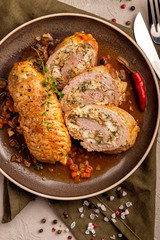 Baked meat rolls in a thick vegetable sauce. A large portion of sliced meat on a plate. Close up and vertical view.