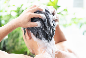 Closeup young man washing hair with shampoo from outdoor, health care concept, selective focus