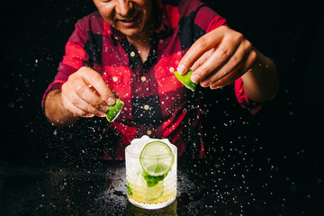 Barman squeezing lime making Caipirinha cocktail