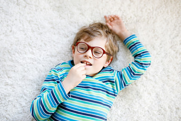 Close-up portrait of little blond kid boy with brown eyeglasses